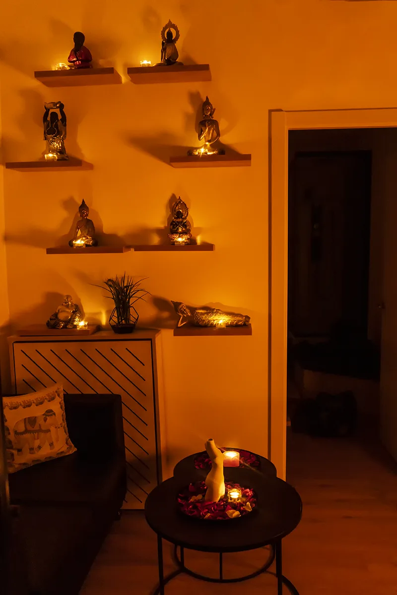 Recibidor con budas sobre estantes, velas encendidas y una mesa con pétalos de rosa, centro erótico en Zaragoza