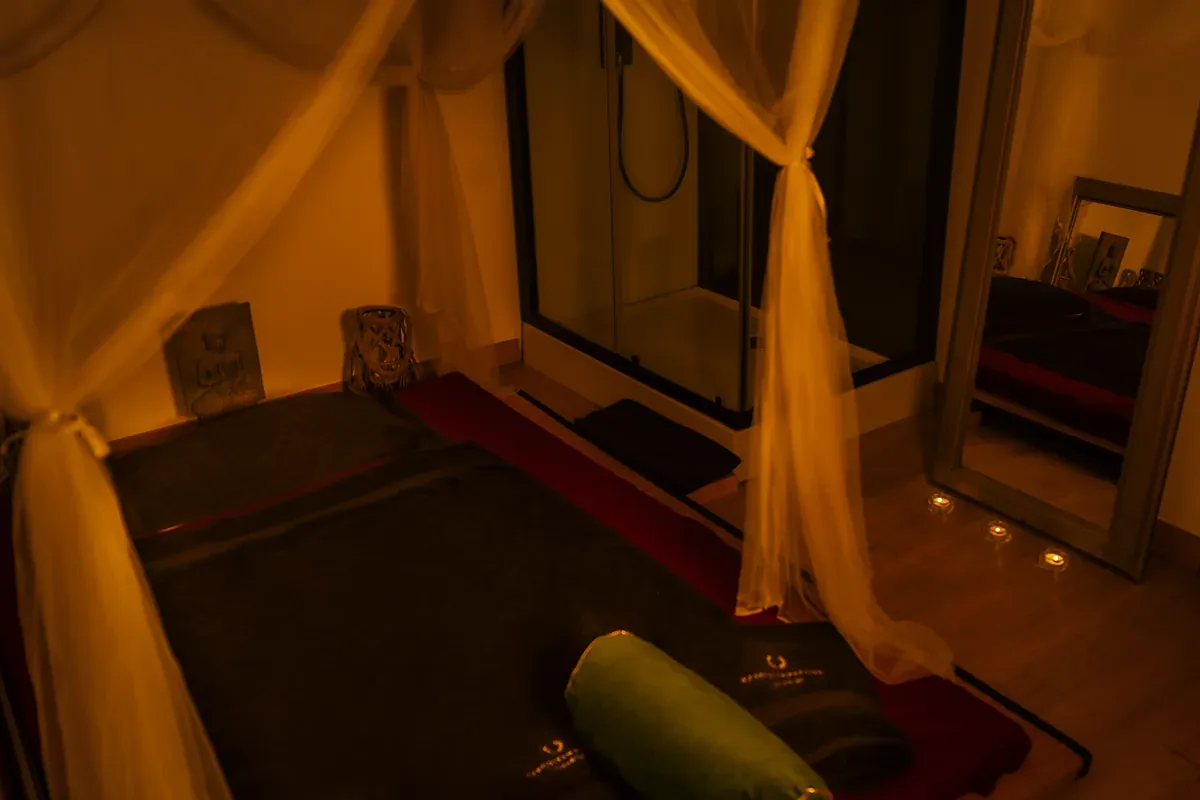 Floor mattress with dark towels and a green cushion, erotic massage centre in Zaragoza