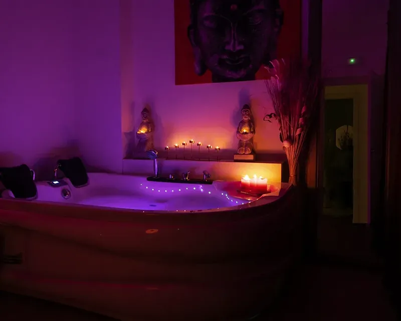 Jacuzzi con luz violeta y velas encendidas en el borde, masaje nudista en Zaragoza