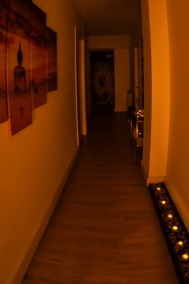 Pasillo del centro con cuadros de Buda y una hilera de velas encendidas sobre piedras, masajes eróticos cerca de mí en Zaragoza