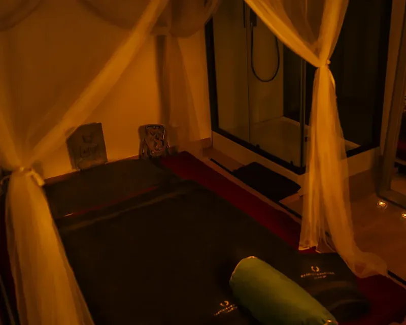 Colchoneta en el suelo con toallas negras y un cojín verde, dosel de gasa, masajes eróticos para mujeres tantra Zaragoza