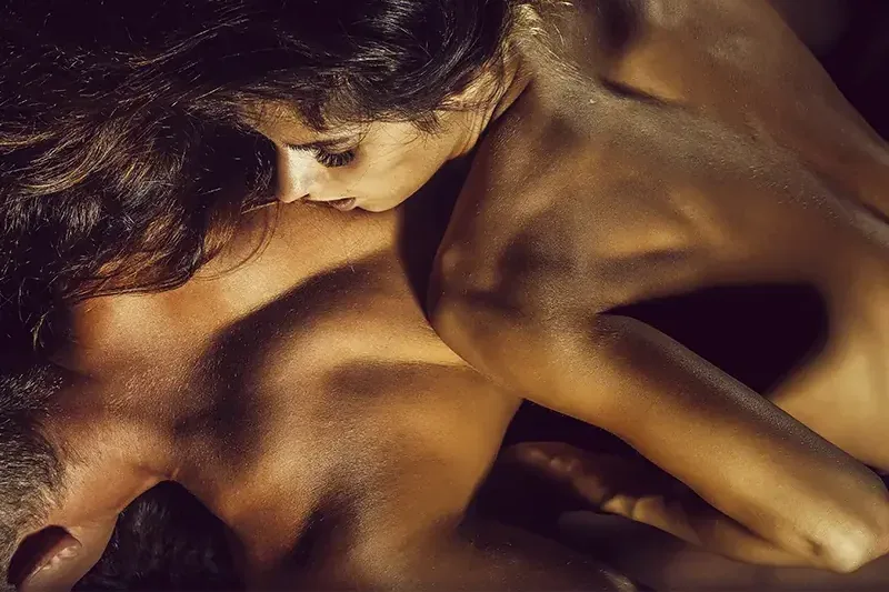 Una mujer morena apoya el rostro y besa el hombro de un hombre, spa erótico hombres en Zaragoza